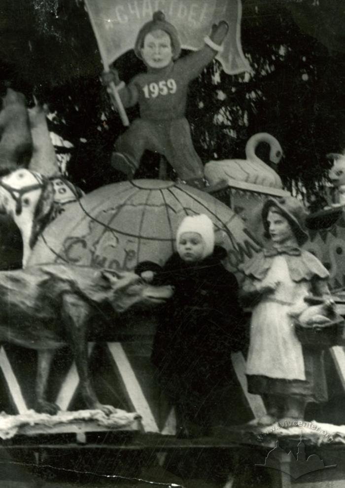 Дитина на фоні іграшкових фігур та міської ялинки напередодні 1959 року