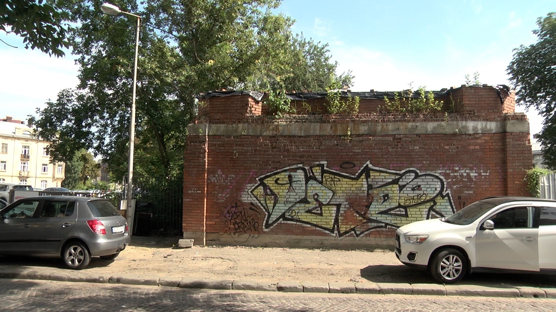 Машини паркуються на розбитих тротуарах, що є частиною однієї з небагатьох площ в районі