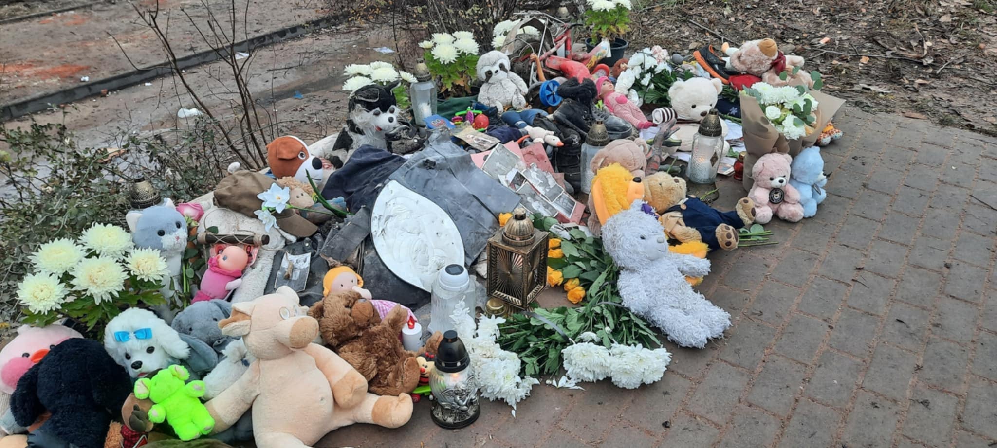 Люди несуть квіти та іграшки до зруйнованого будинку